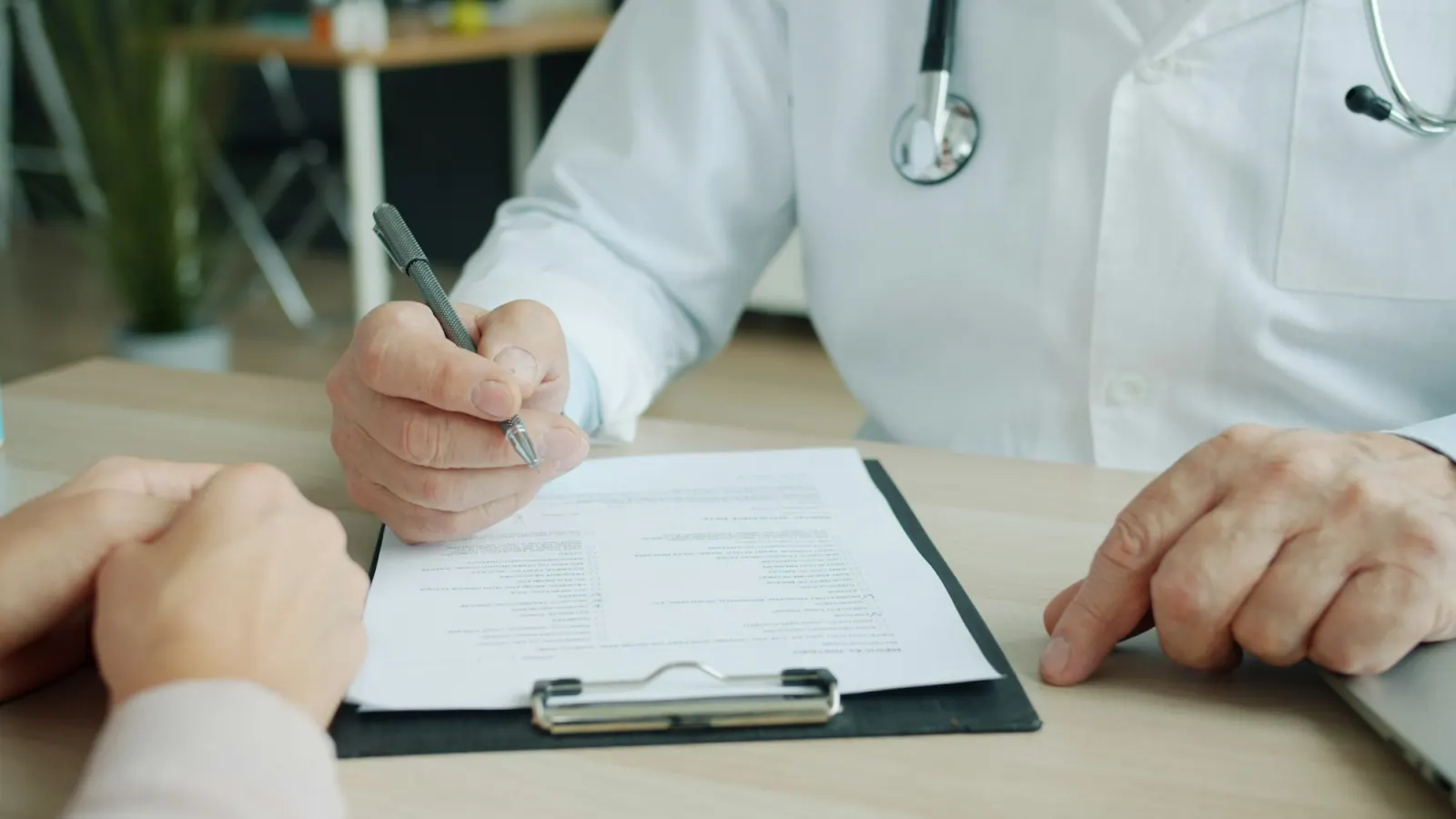 A hand signing a form on a clipboard